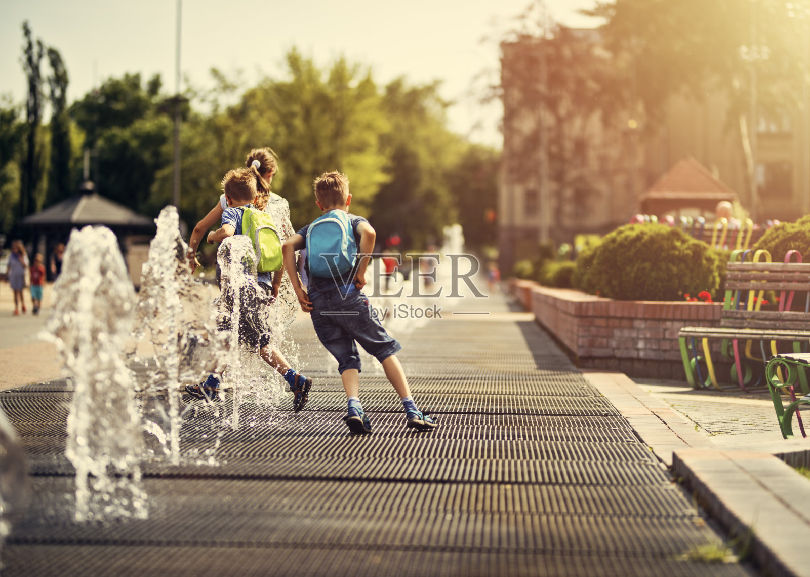 炎炎夏日，孩子们在喷泉间奔跑。照片摄影图片