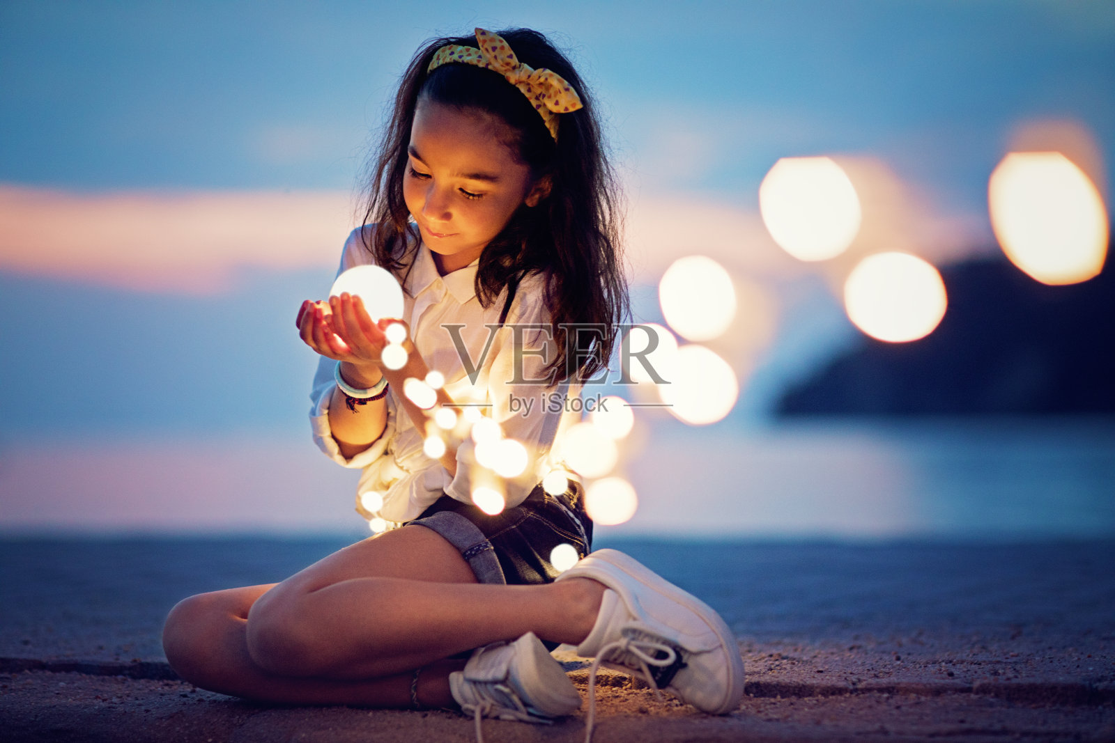 小女孩坐在码头上玩着神秘的灯光照片摄影图片