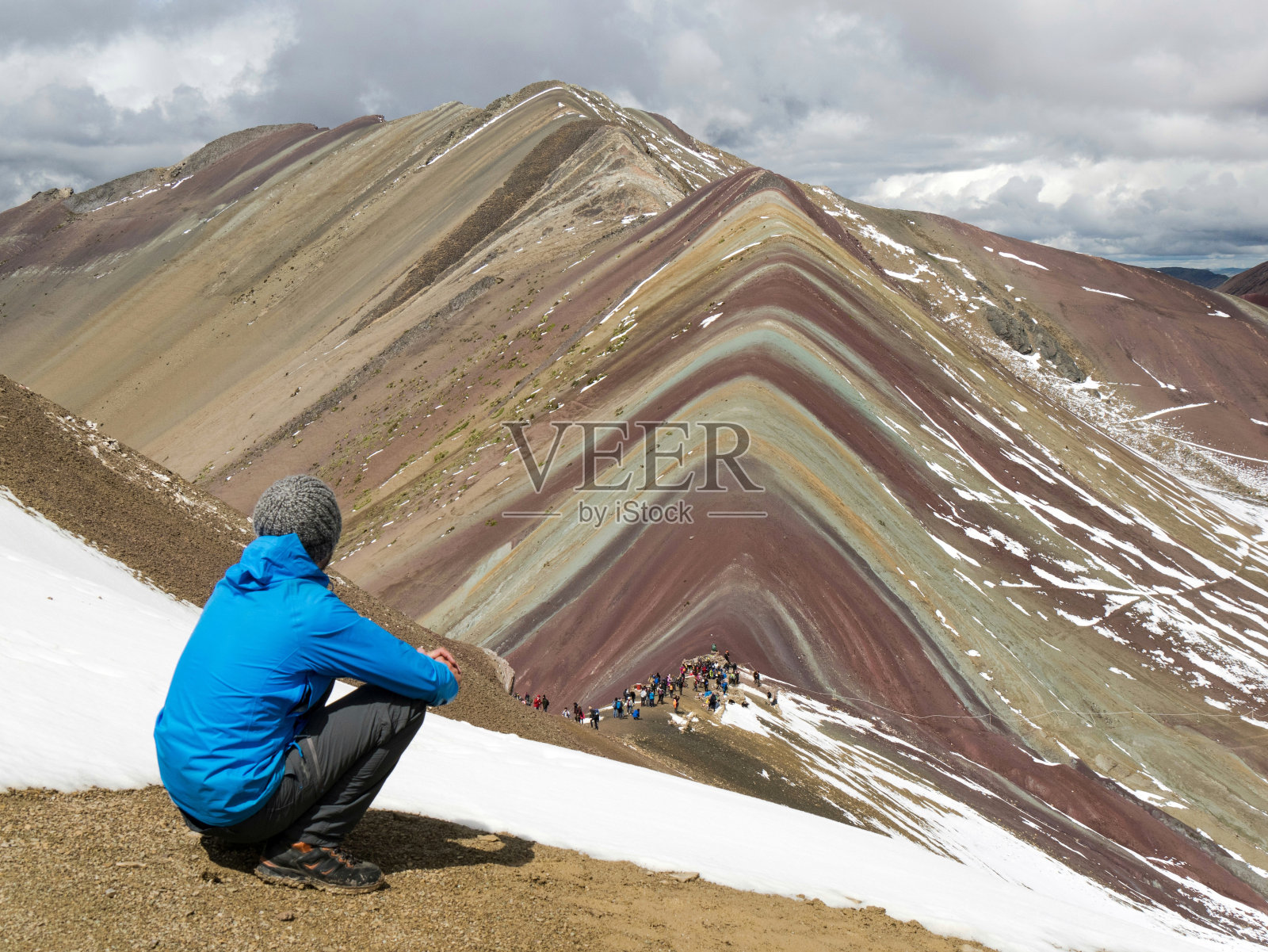 秘鲁库斯科，一个年轻人坐在彩虹山前照片摄影图片