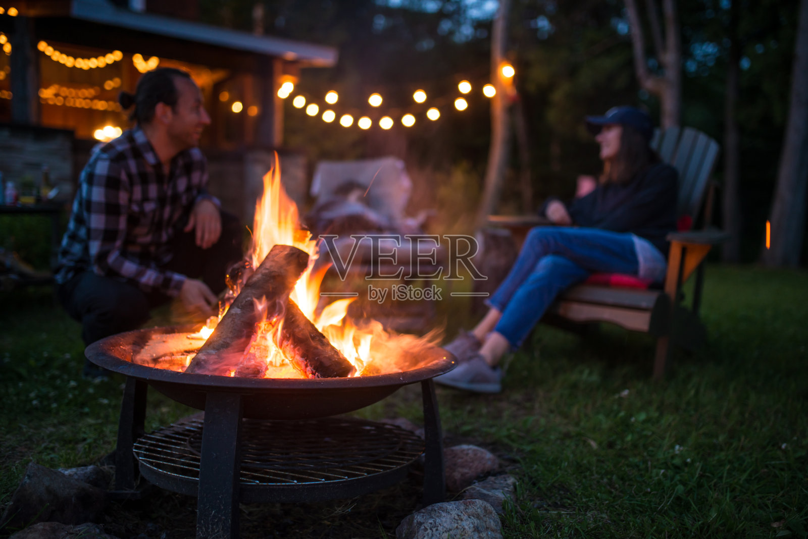 一个年轻的家庭在一个美丽的加拿大小木屋的篝火旁取暖照片摄影图片