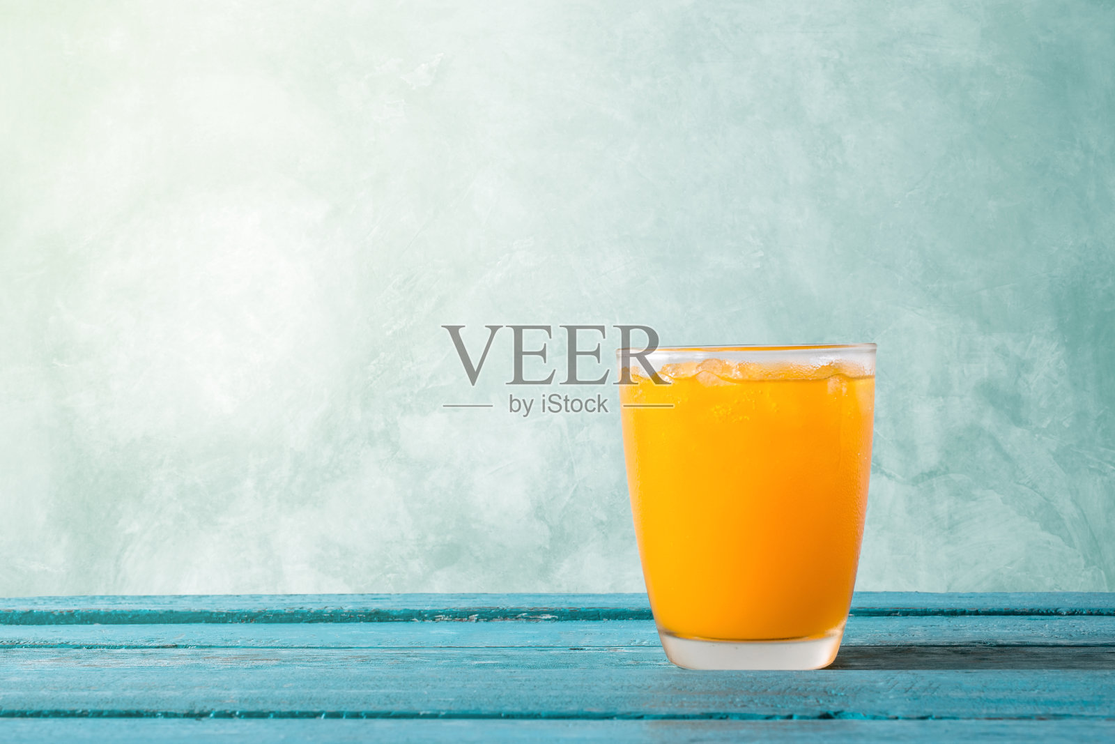 橙汁在玻璃与冰在海洋蓝色木制夏季时间概念。照片摄影图片