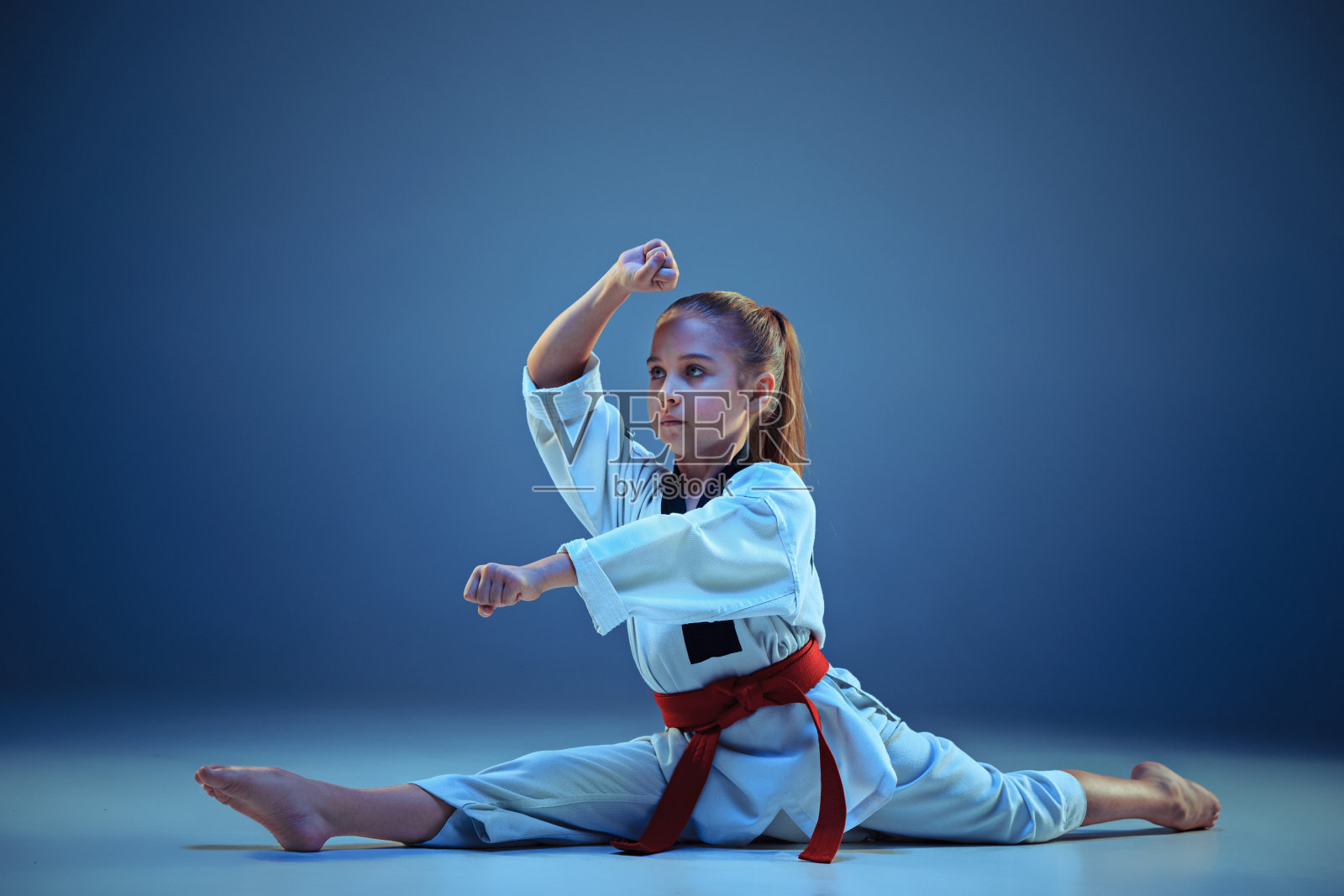 年轻女孩训练空手道在蓝色的背景照片摄影图片