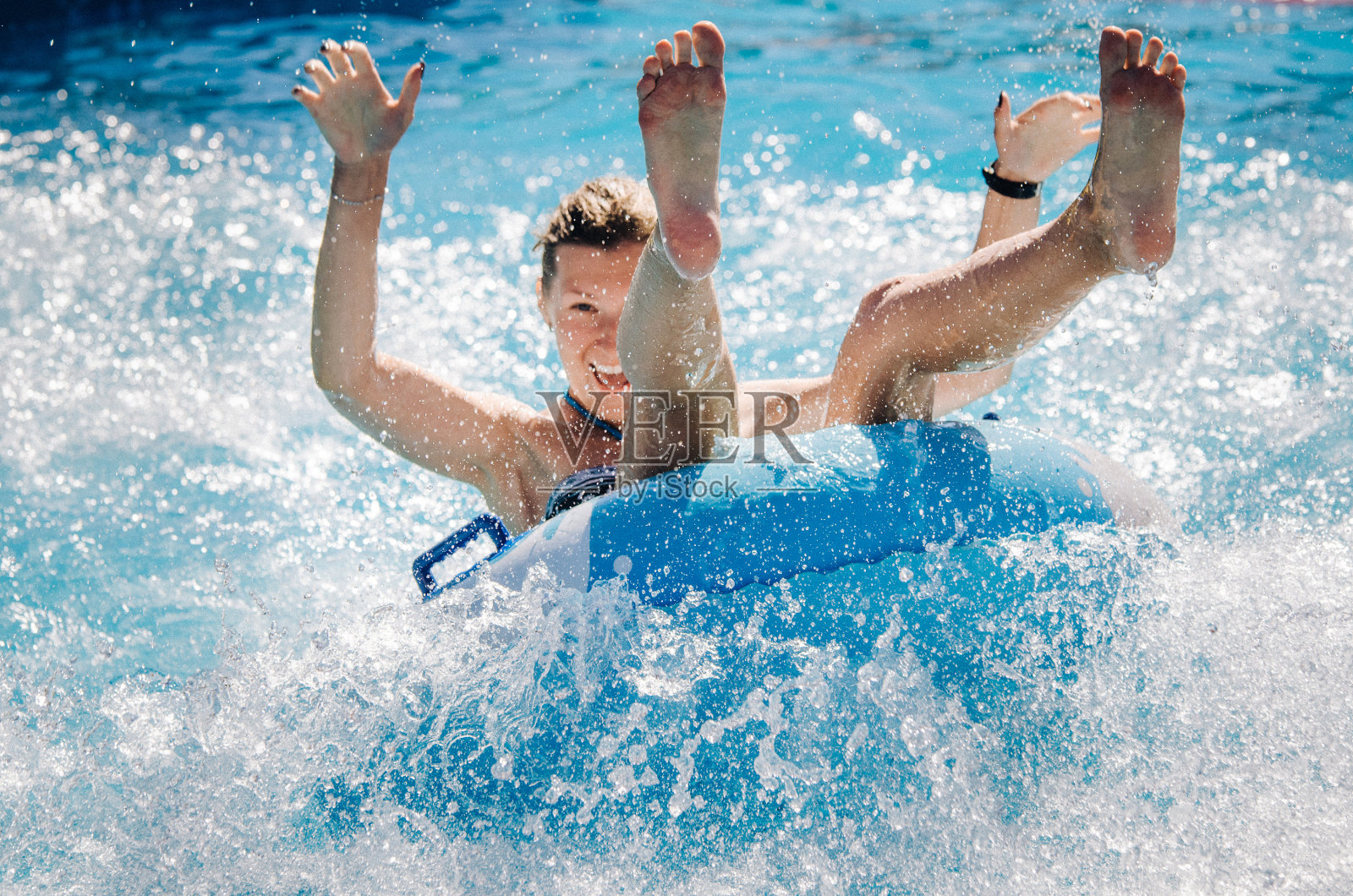 一对有趣的夫妇在一个浮子上玩水上飞车，溅起水花。暑假的概念。照片摄影图片