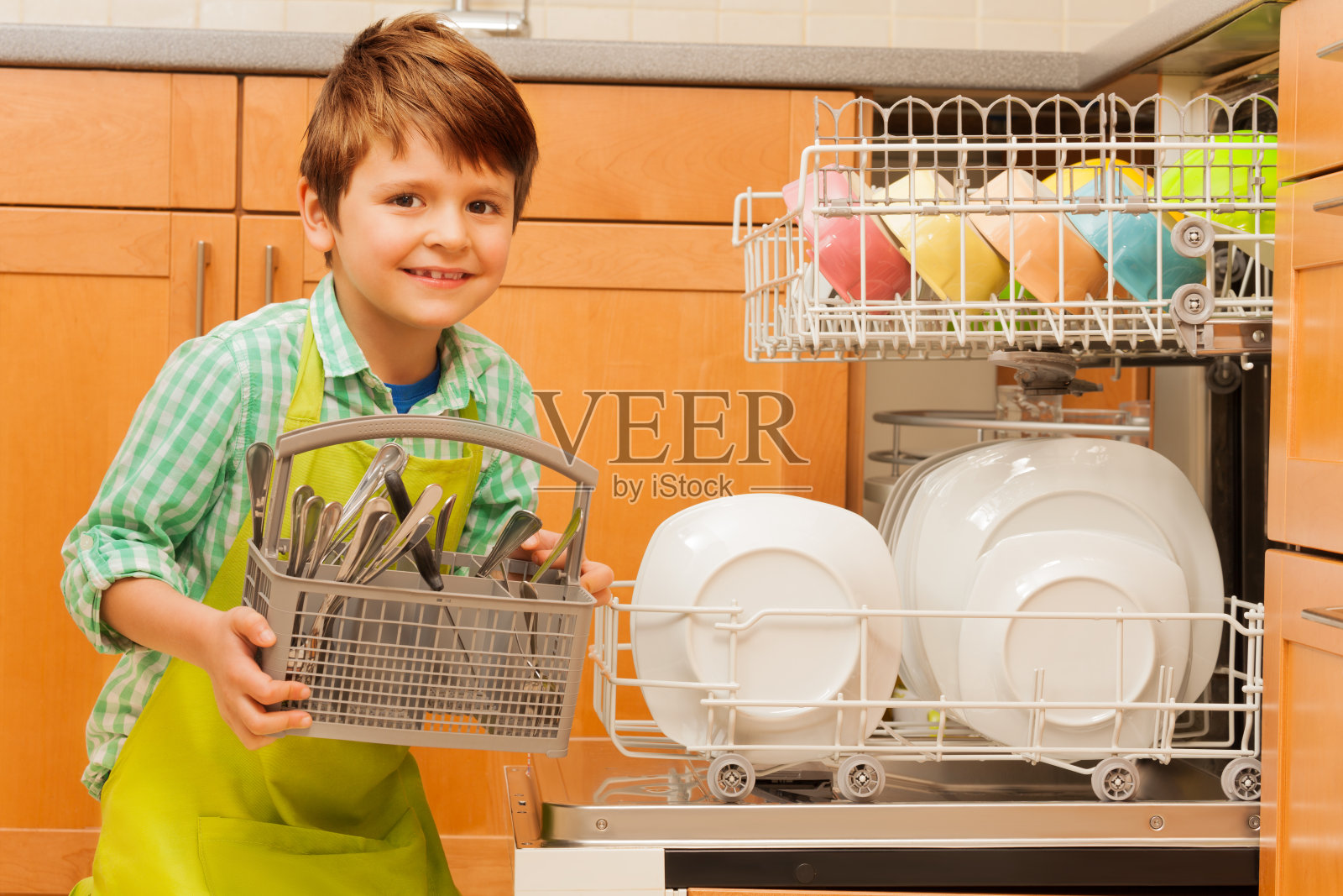 快乐男孩从洗碗机里拿出餐具照片摄影图片