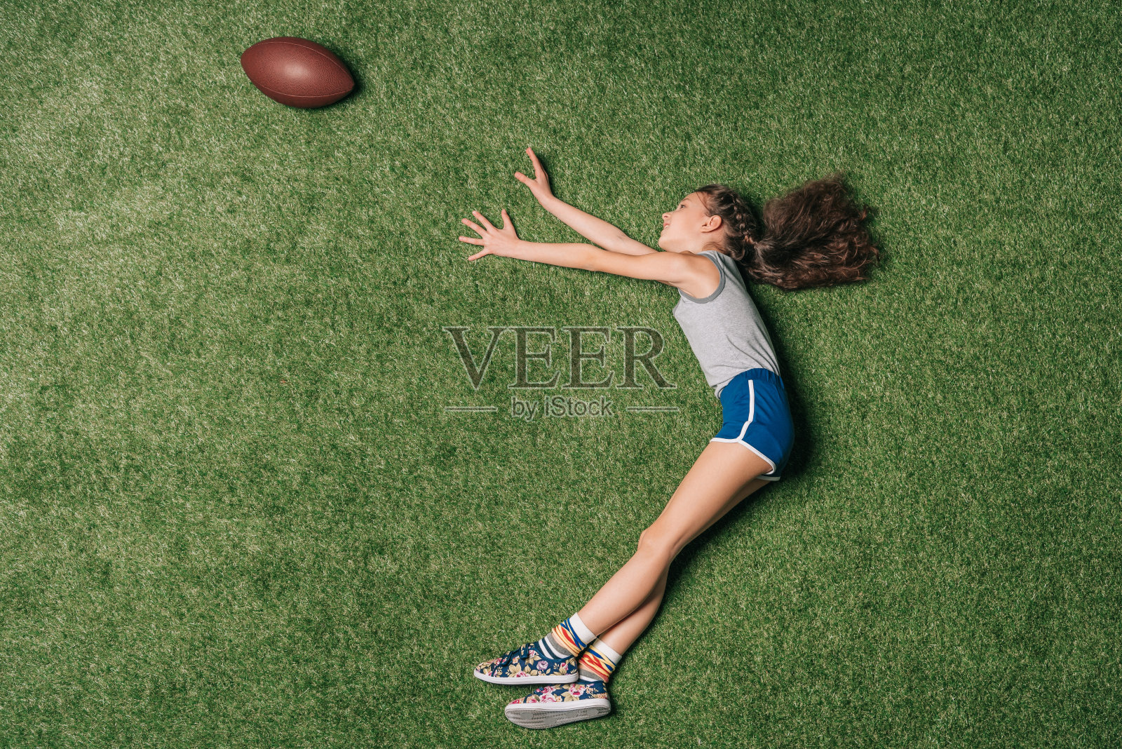 俯视图的小运动女孩在草地上抓橄榄球，体育儿童的概念照片摄影图片