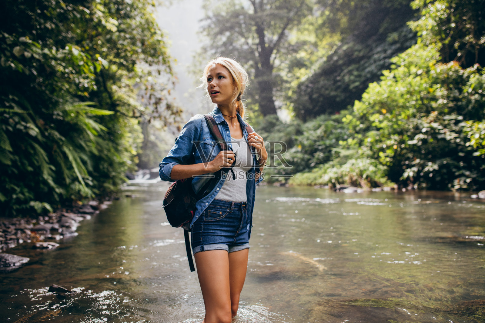 一个背着背包的漂亮女人站在小溪边照片摄影图片