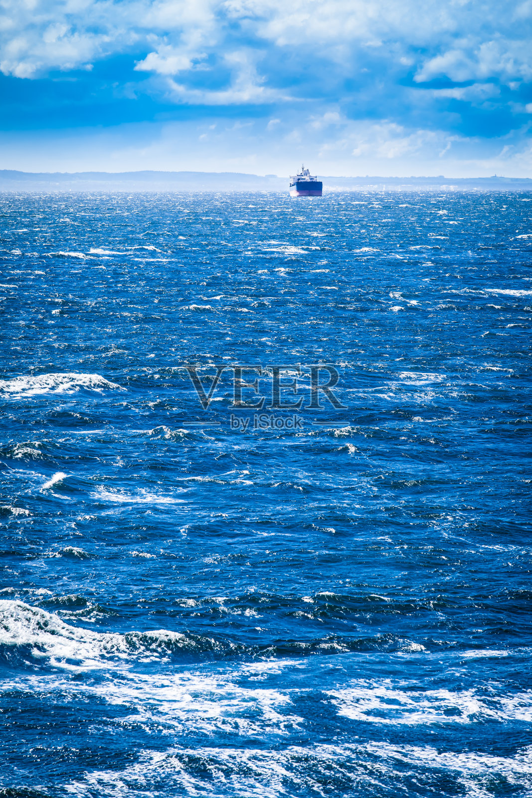蓝色波涛汹涌的大海和货轮照片摄影图片