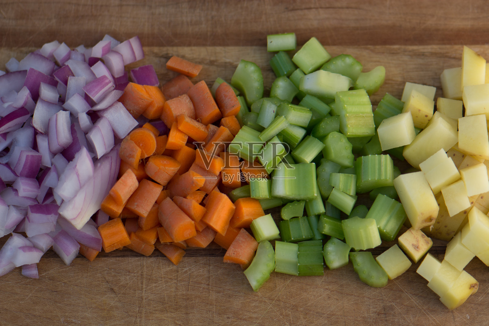 切碎的红洋葱，胡萝卜，芹菜和土豆放在木砧板上照片摄影图片