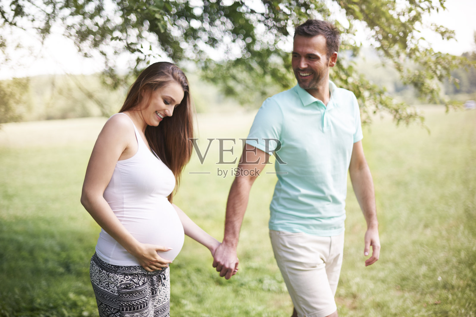 孕妇和丈夫在草地上散步照片摄影图片