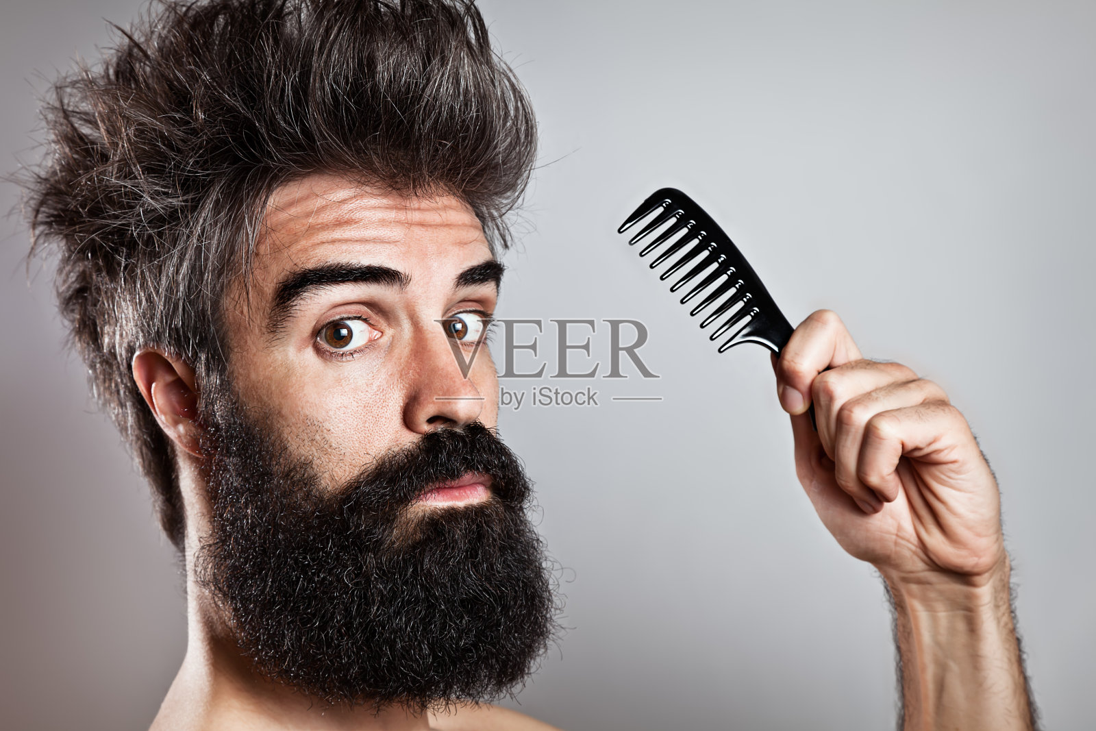 头发凌乱的大胡子男人拿着梳子看着走来照片摄影图片