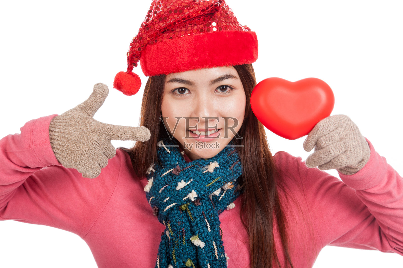 亚洲女孩与圣诞帽指向红色的心照片摄影图片