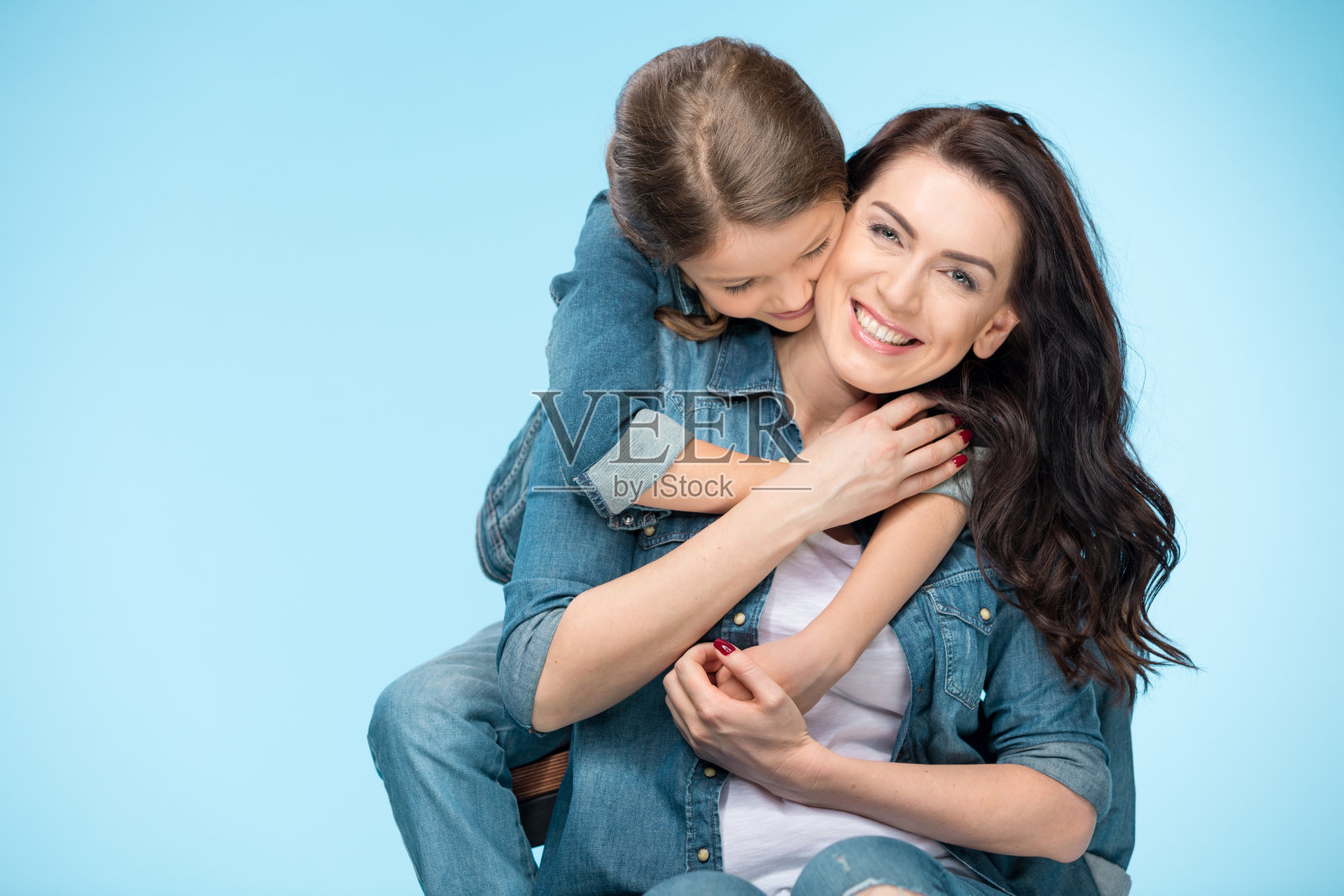 幸福的母亲和女儿拥抱在工作室蓝色的肖像照片摄影图片