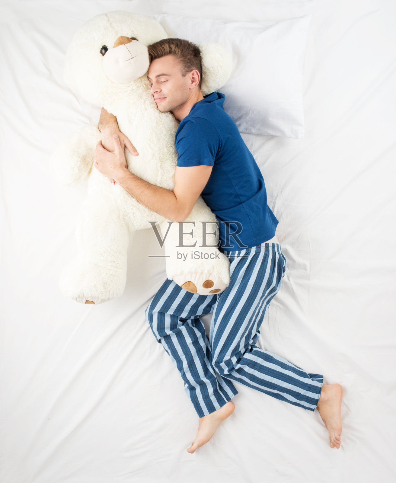 男人和大泰迪熊睡觉照片摄影图片