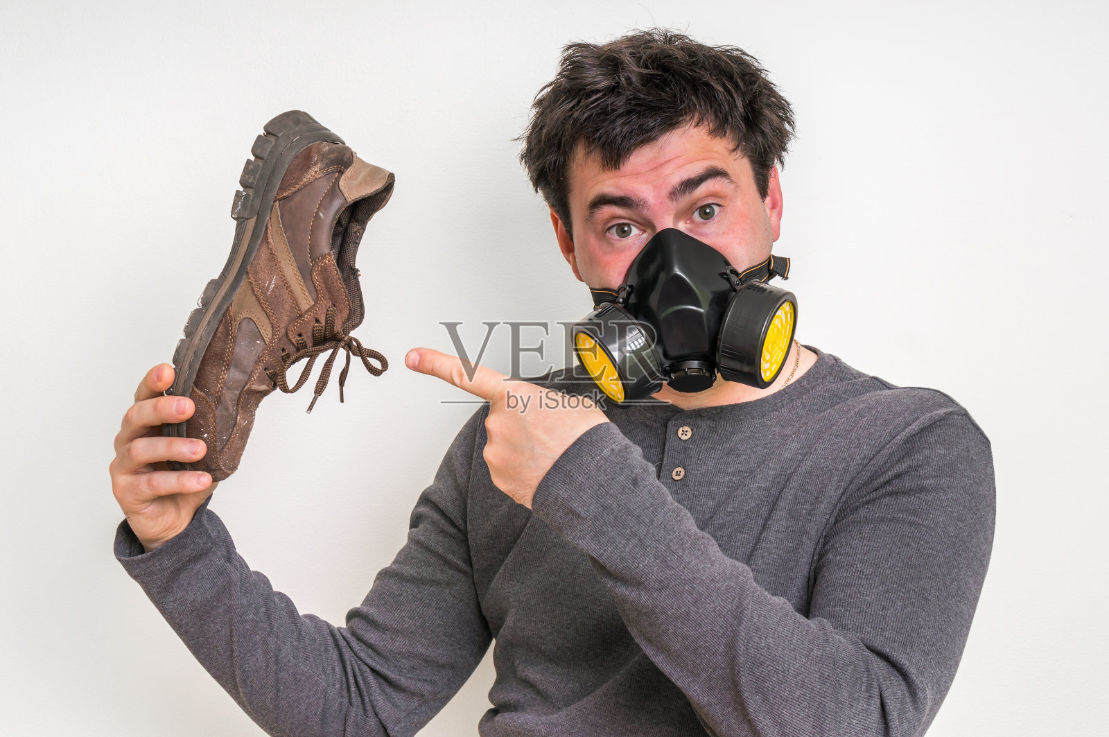 一个戴着防毒面具的人拿着一只又脏又臭的鞋照片摄影图片
