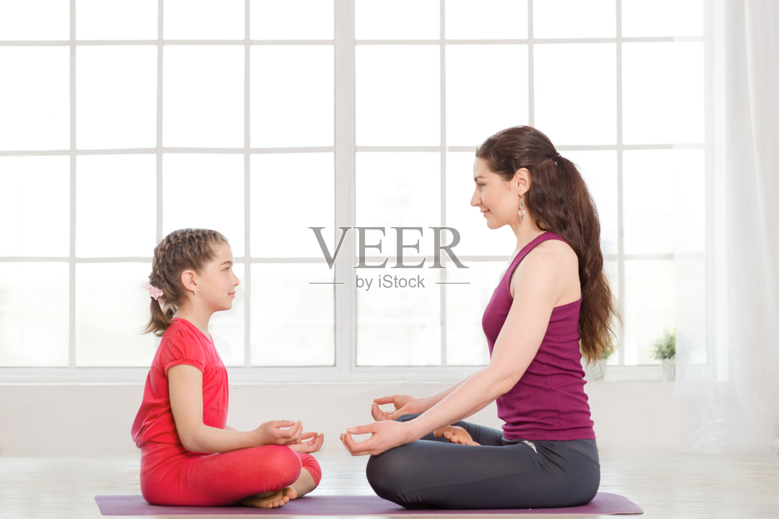 年轻的母亲和女儿在做瑜伽练习照片摄影图片