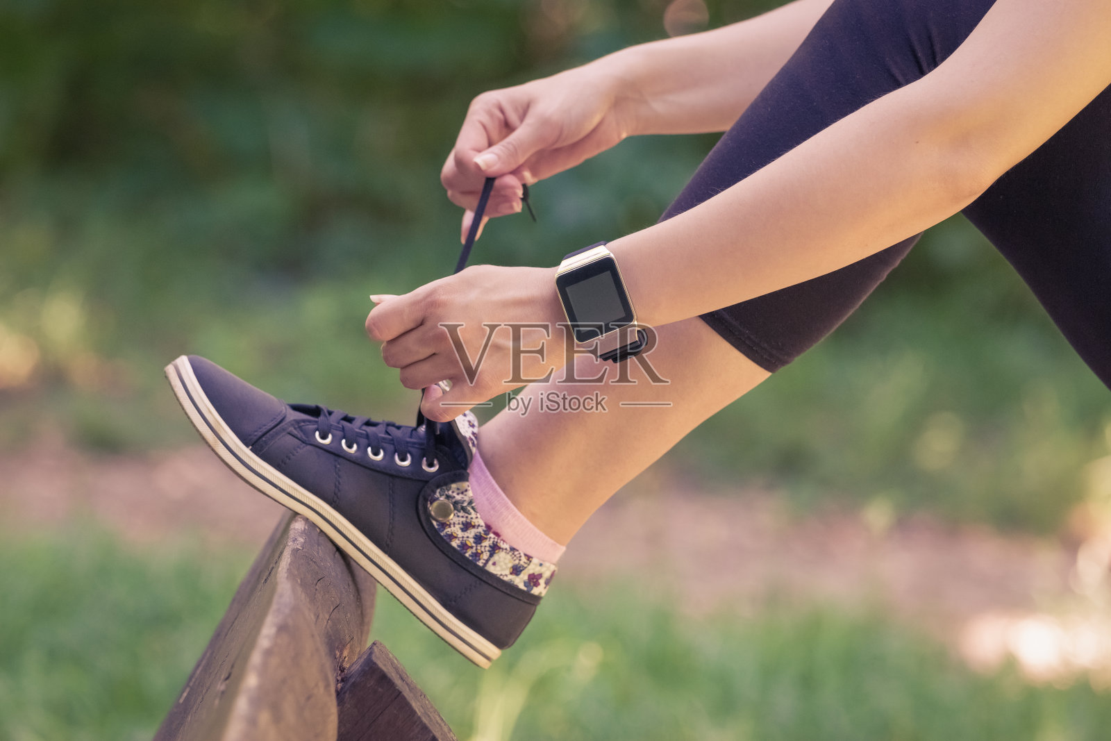 女性戴着智能手表和系鞋带在公园里照片摄影图片