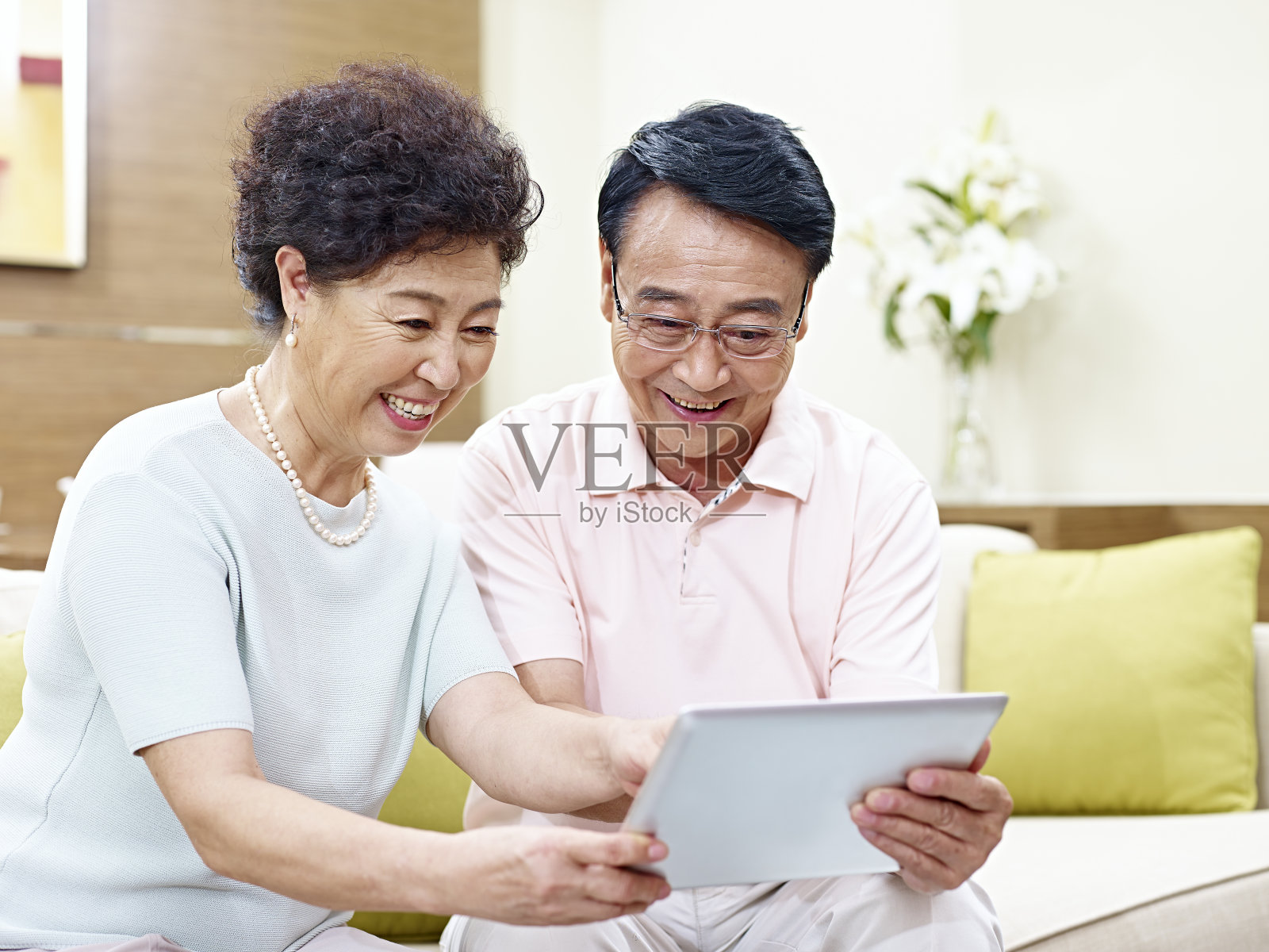 一对亚洲老年夫妇在家里使用数码平板电脑照片摄影图片