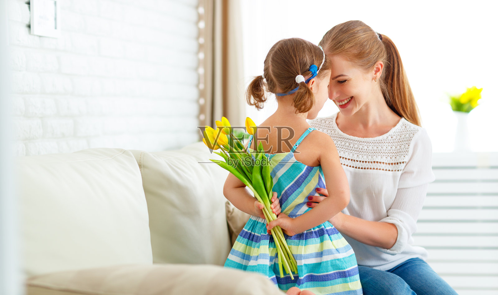 母亲节快乐!女儿向妈妈祝贺，并送给她一张明信片和鲜花照片摄影图片