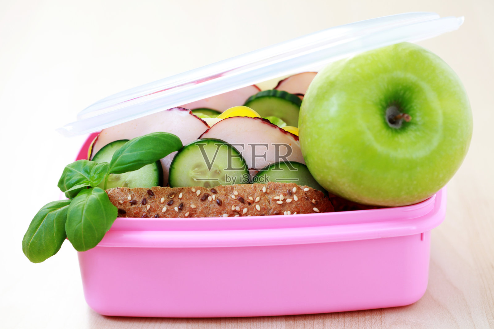 粉红色的午餐盒，里面有一个三明治和一个青苹果吃照片摄影图片