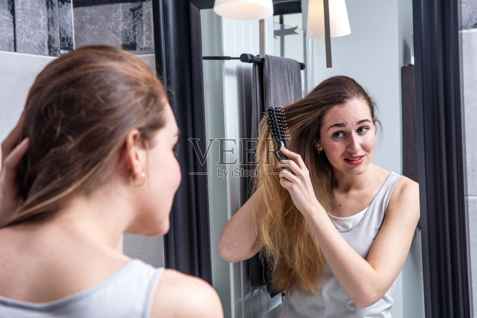 一位美丽的年轻女子正在梳理她干枯纠结的长发照片摄影图片