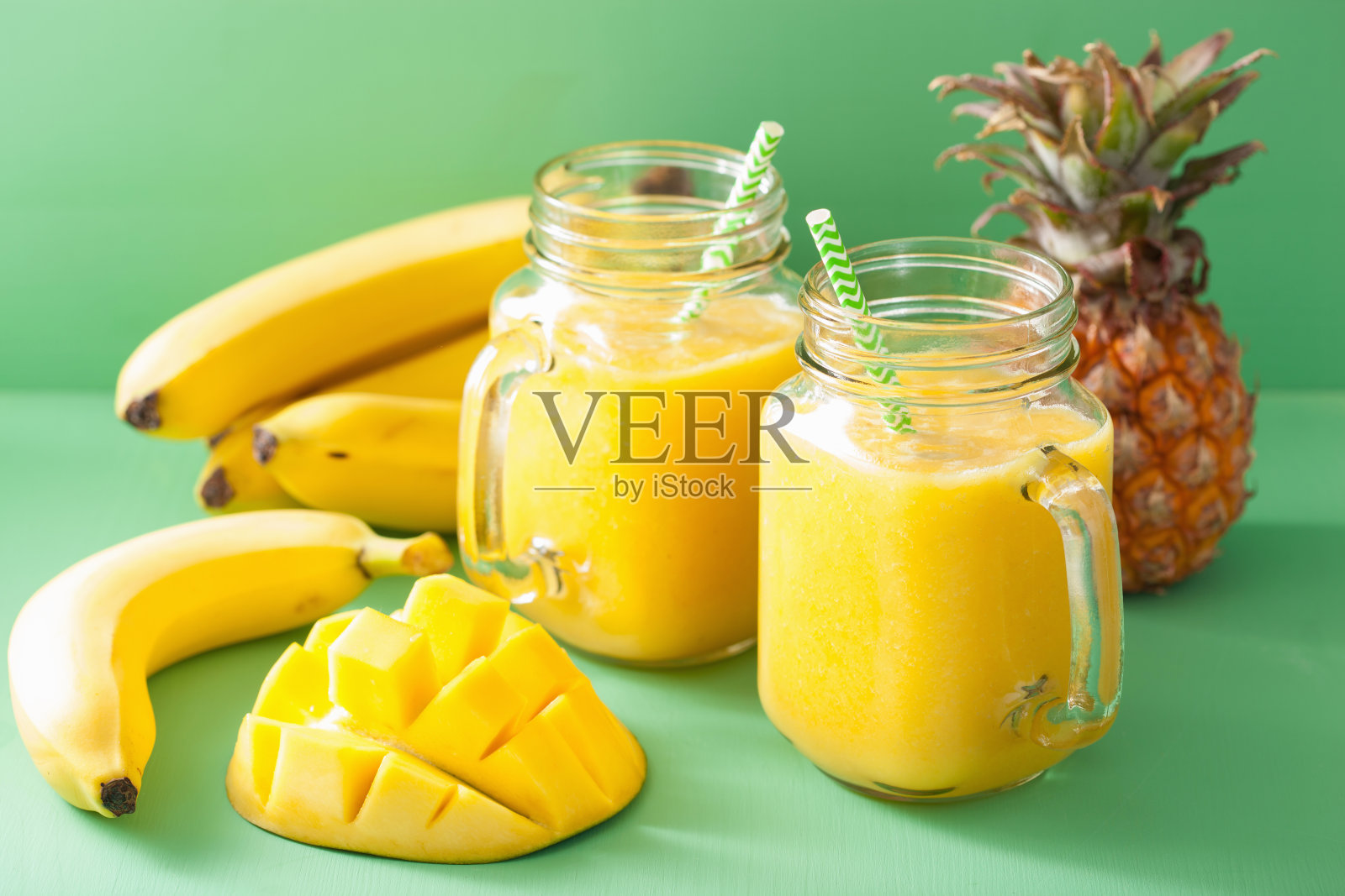健康的黄色冰沙，芒果，菠萝，香蕉在mason罐子照片摄影图片