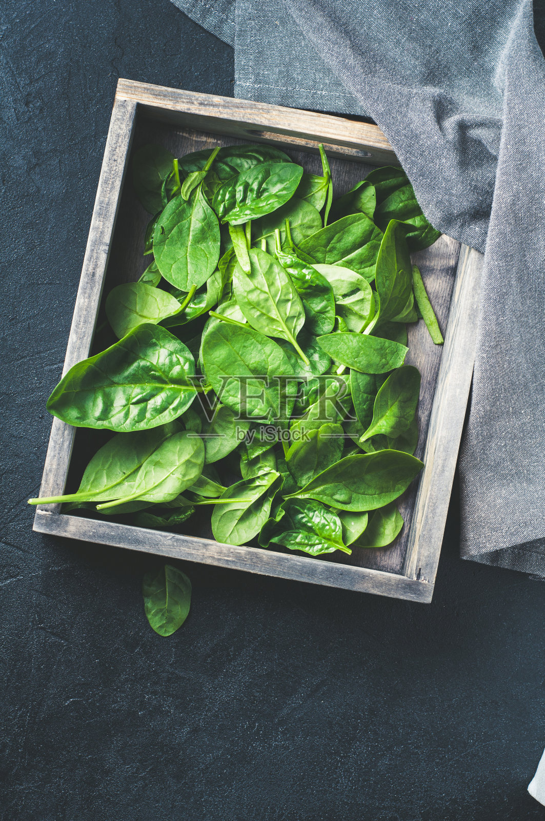 木盒里的新鲜菠菜，背景是深色的混凝土。垂直的框架。饮食或减肥的概念照片摄影图片