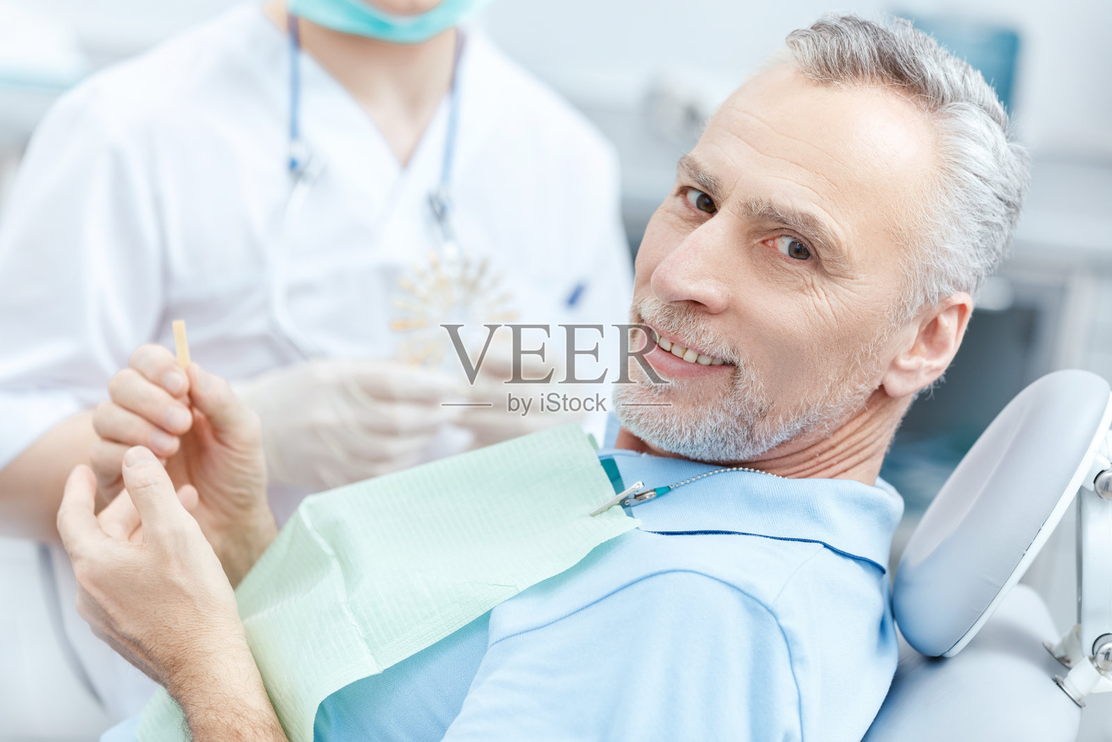 成熟的病人在看牙医时查看牙齿样本照片摄影图片
