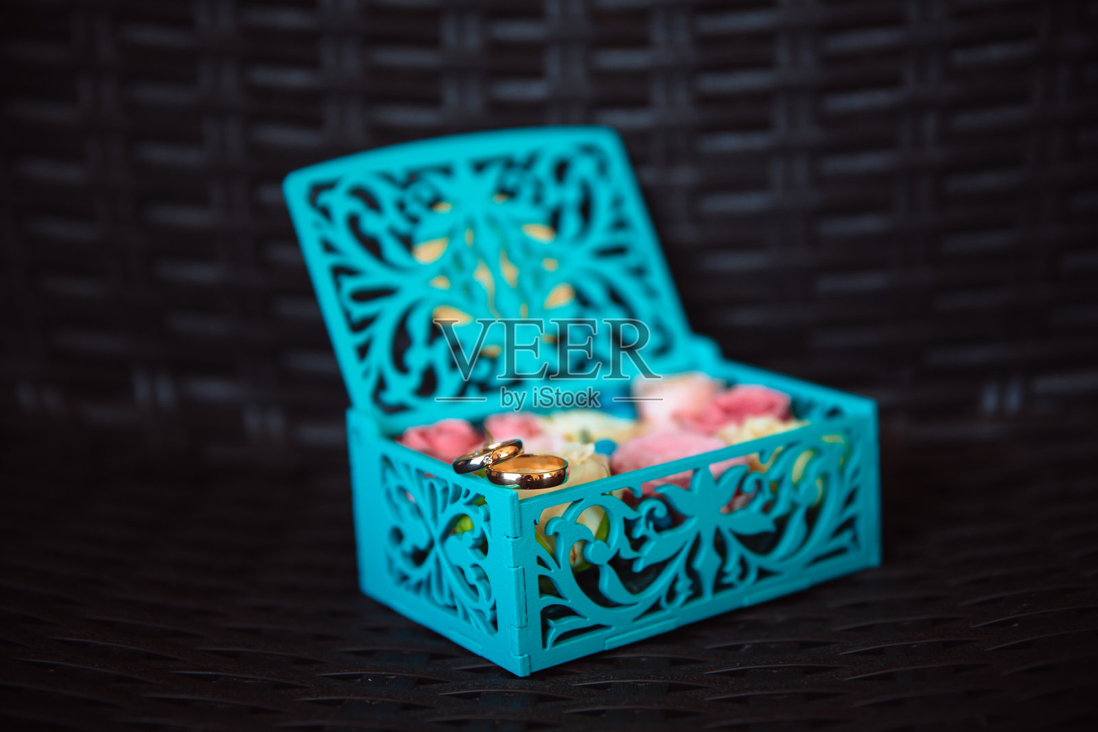 黑色背景上的蓝色木箱里装着结婚金戒指。爱的概念照片摄影图片