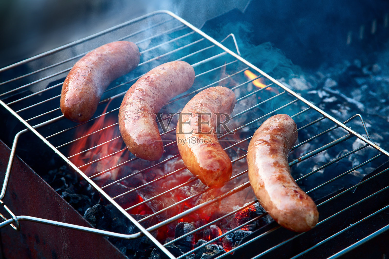 四根美味多汁的香肠放在火炭烤架上照片摄影图片