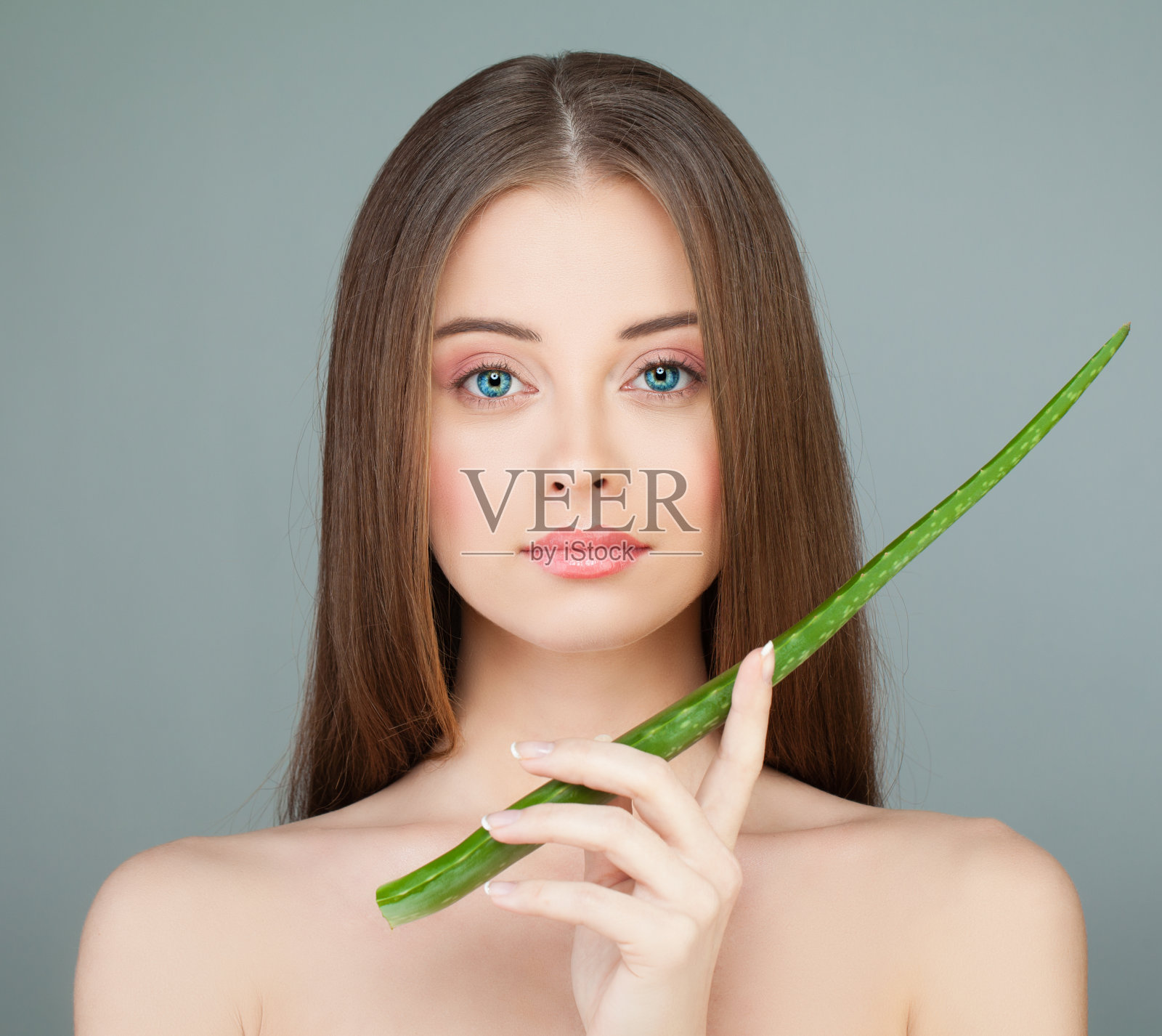 健康的模特女孩抱着绿色的芦荟叶。皮肤护理的概念照片摄影图片