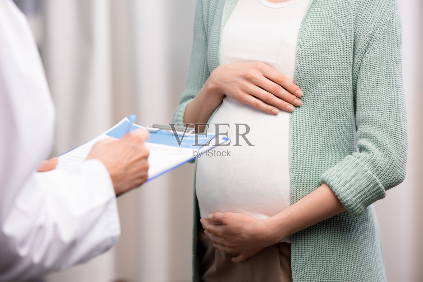 医生写下来时孕妇抱着肚子的镜头照片摄影图片