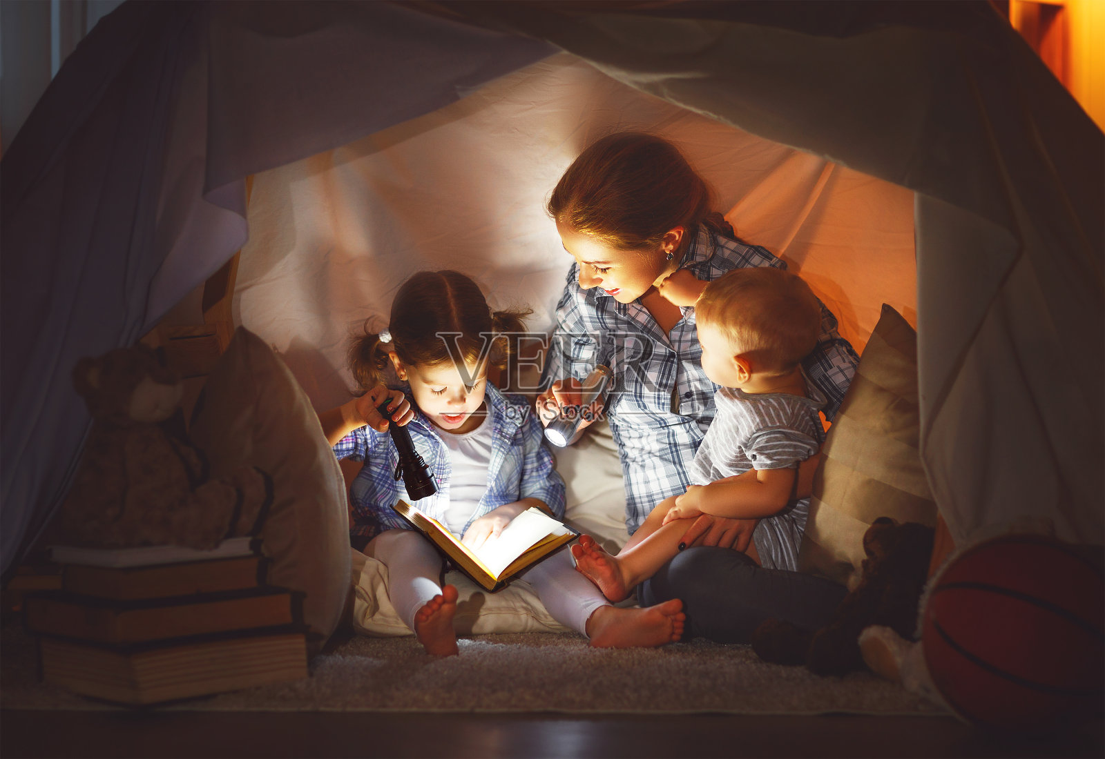 幸福的家庭妈妈和孩子们在家里的帐篷里看书照片摄影图片