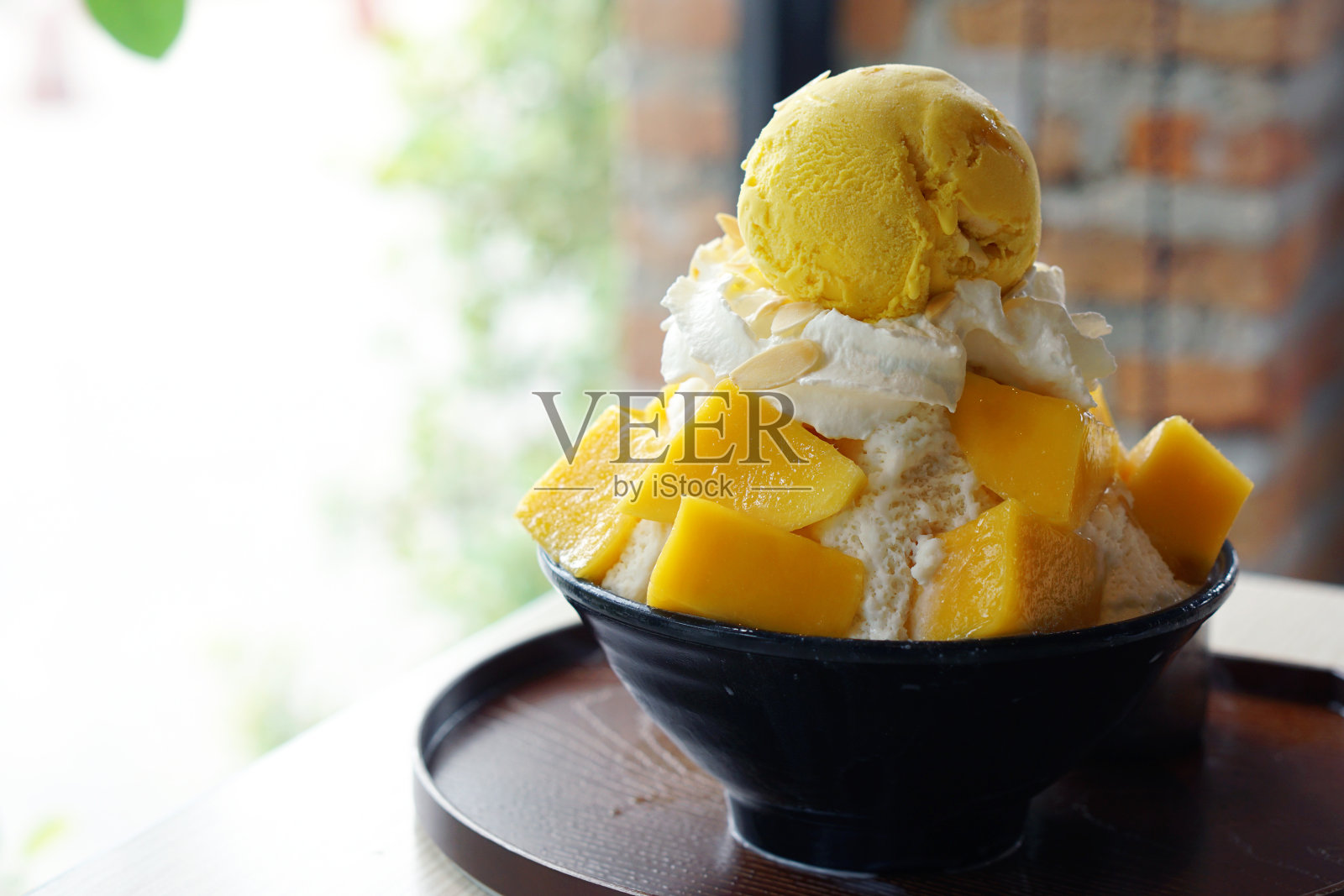 芒果刨冰，也被称为芒果冰苏韩国甜点，与糯米，鲜奶油和芒果冰淇淋一起放在桌子上。照片摄影图片