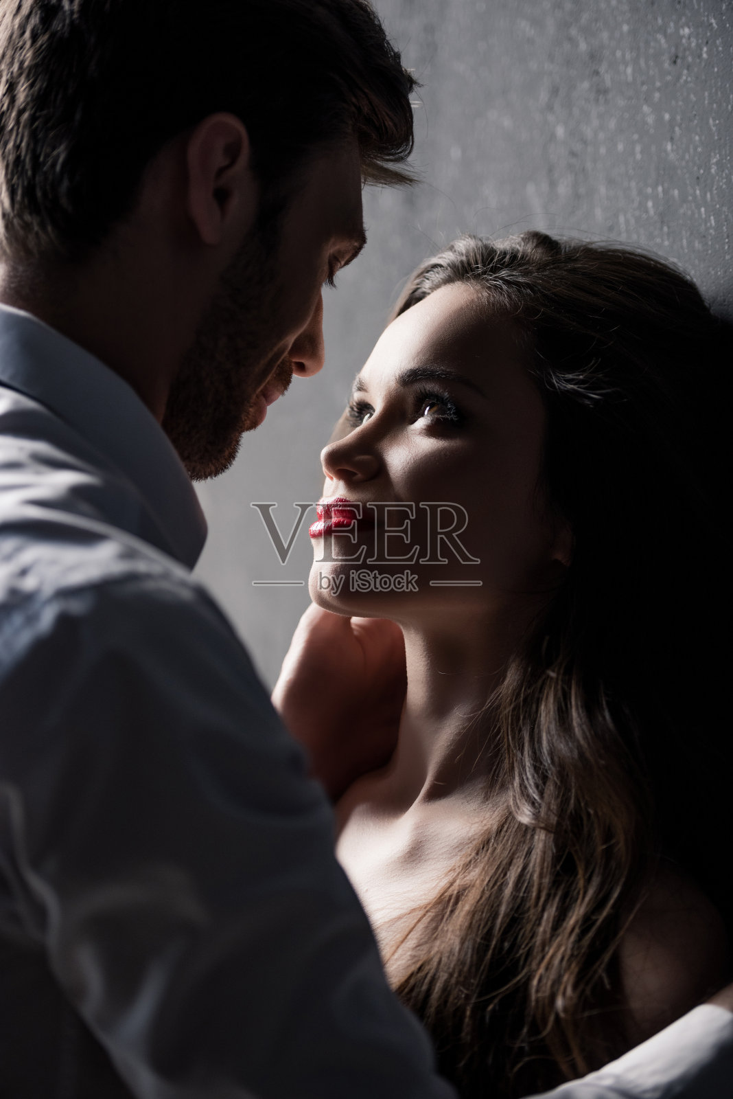 年轻的感性夫妇可以亲吻，而站在墙边照片摄影图片