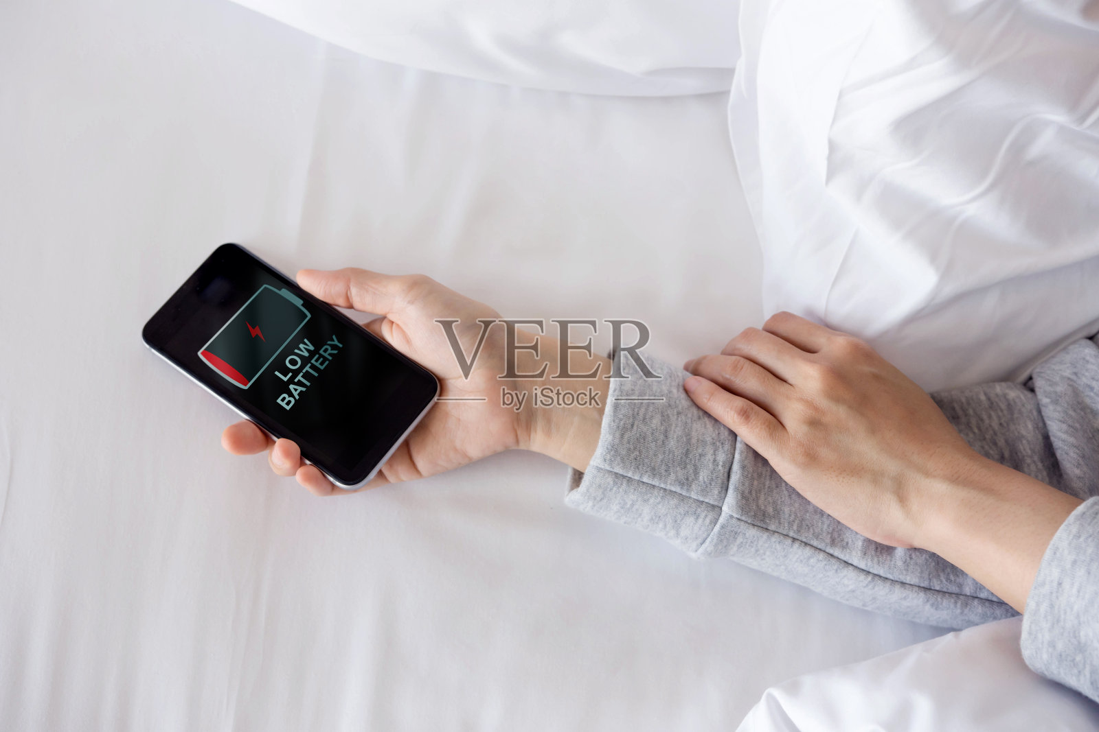 女人睡觉时把手机放在床上，电量不足，需要充电或休息照片摄影图片