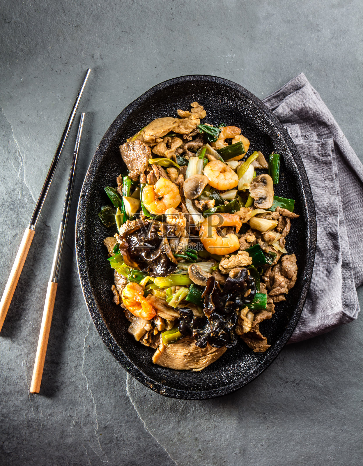 中国菜。Te pam圣。一锅炸牛肉，猪肉，鸡肉，虾，香菇，冠军和葱。配以灰色石板背景的米饭。照片摄影图片