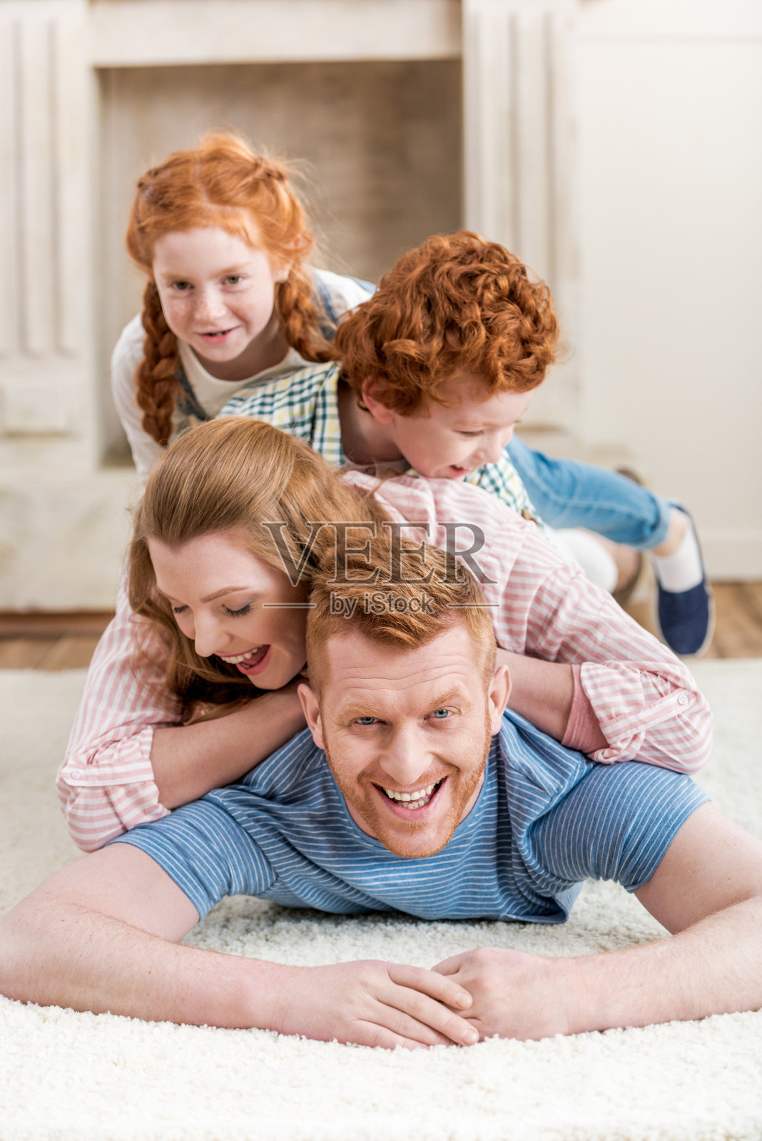 漂亮快乐的红发家庭一起在地毯上玩，大全家福照片摄影图片