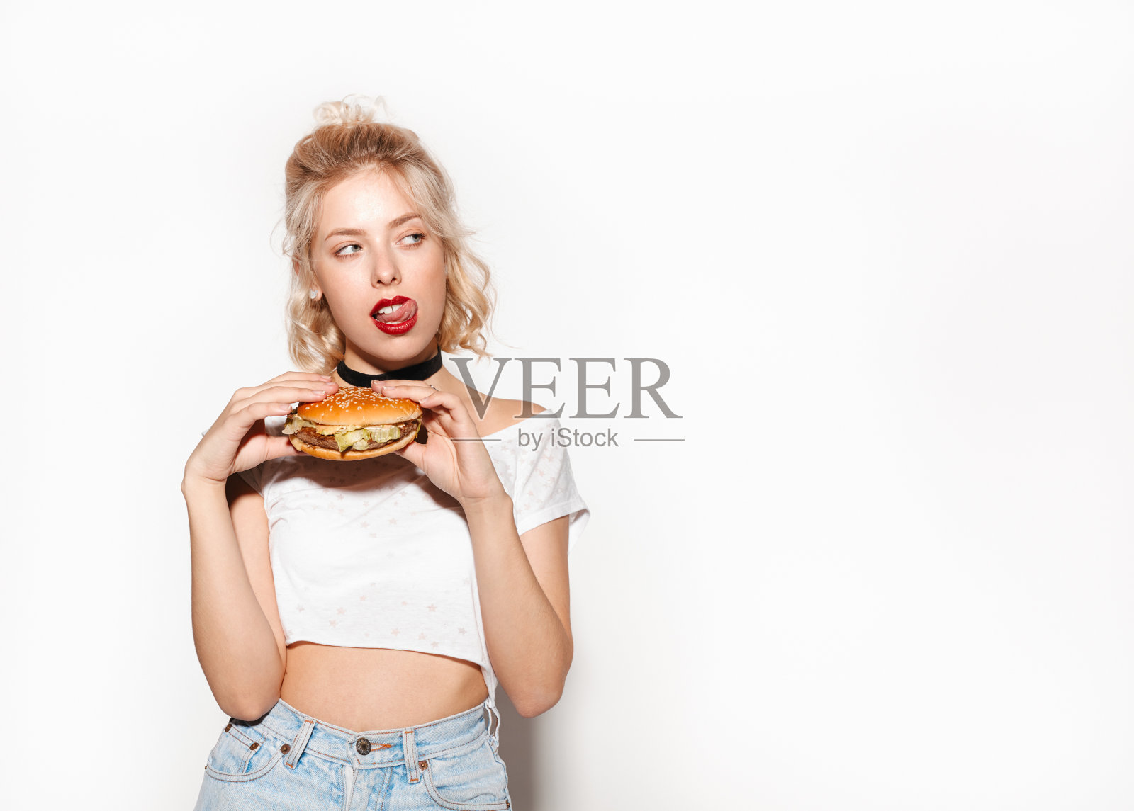 拿着汉堡舔嘴唇的女人照片摄影图片