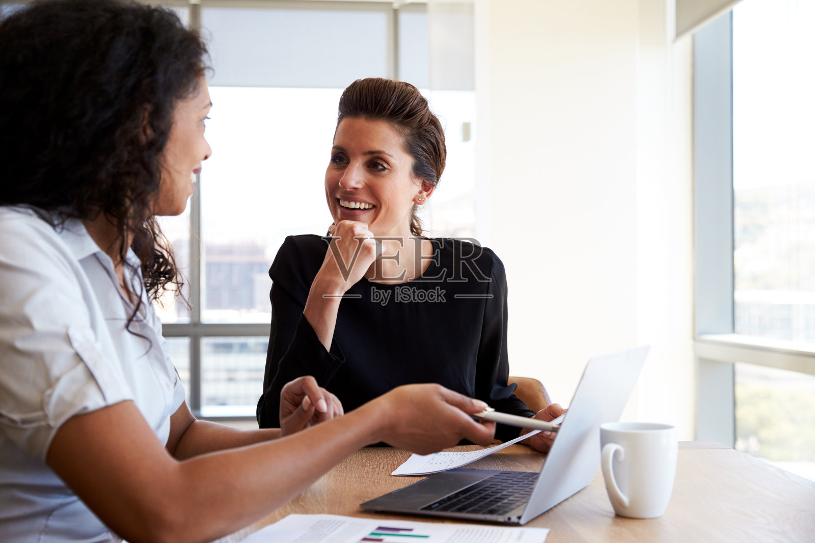 两位商务女性在办公室会议中使用笔记本电脑照片摄影图片