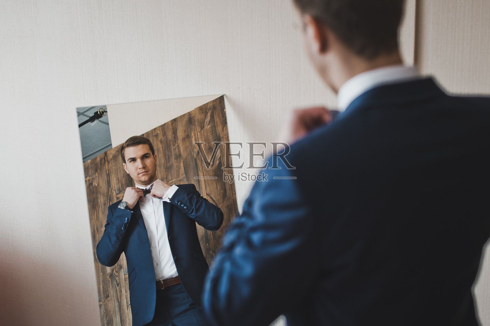 男人在镜子前欣赏自己的衣服。照片摄影图片