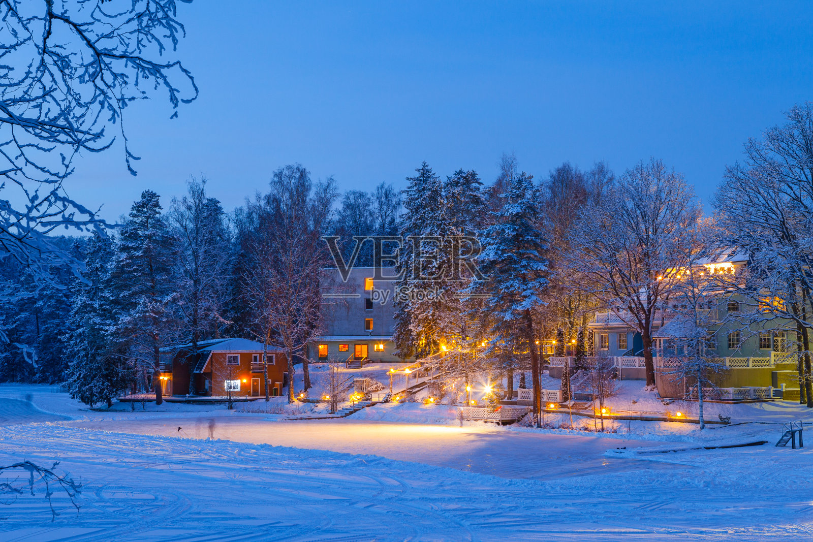 冰雪覆盖的冬天，在结冰的湖附近，照亮了小屋的景象照片摄影图片
