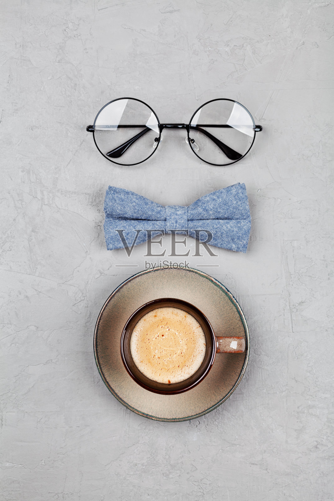 父亲节快乐的背景早上咖啡杯，眼镜和领结在石头灰色的桌子上。平的。照片摄影图片