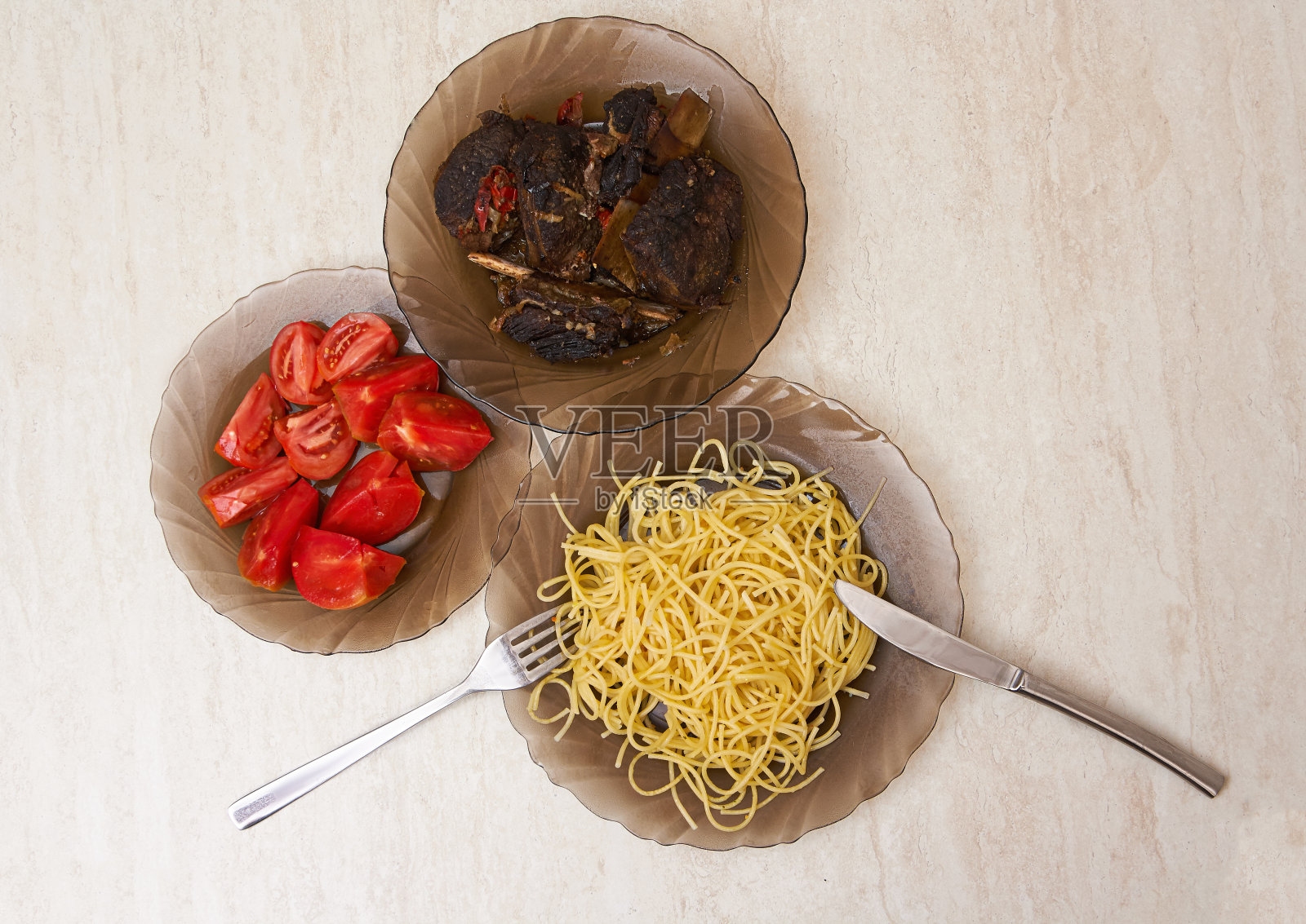桌上放着炒肉、意大利面和西红柿的盘子照片摄影图片