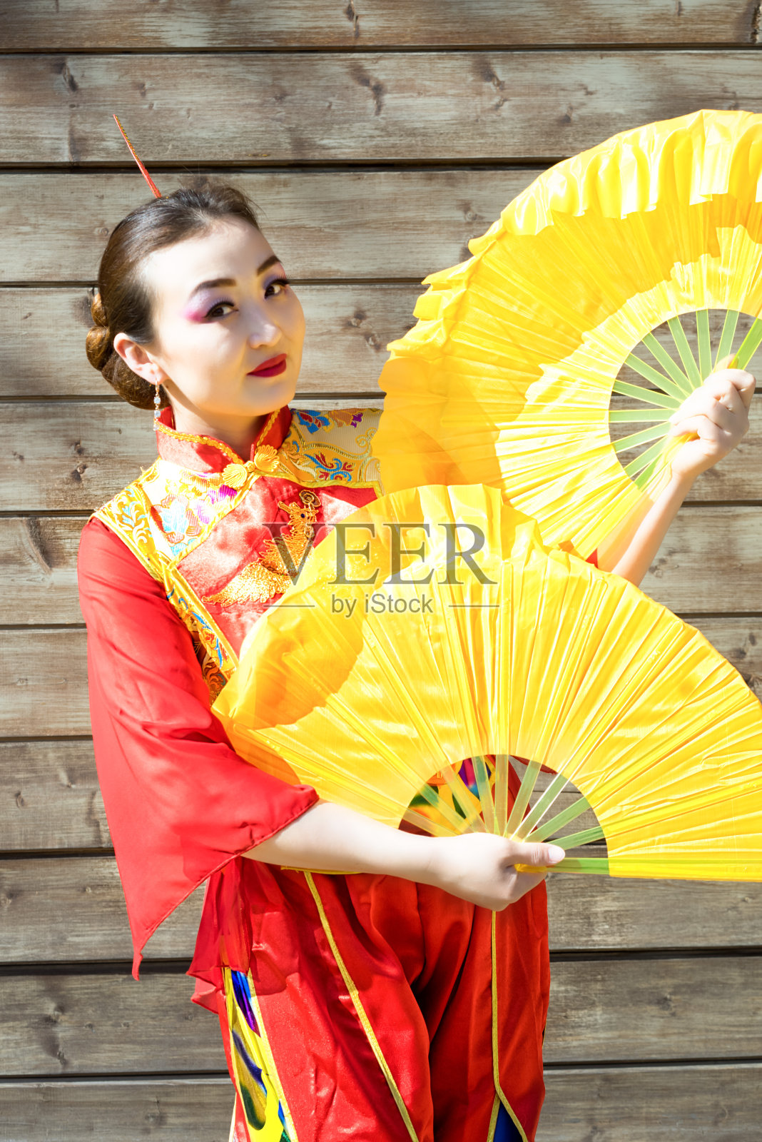 美丽的中国女孩的肖像穿着传统的红色中国服装和两个大的黄色扇子照片摄影图片