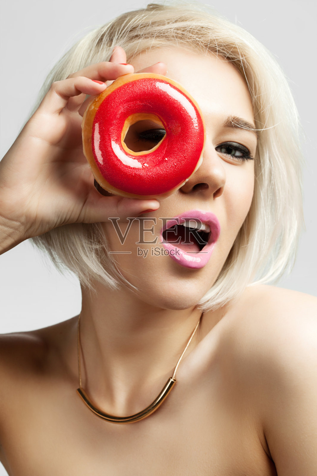 拿着红色糖霜的甜甜圈的女人照片摄影图片