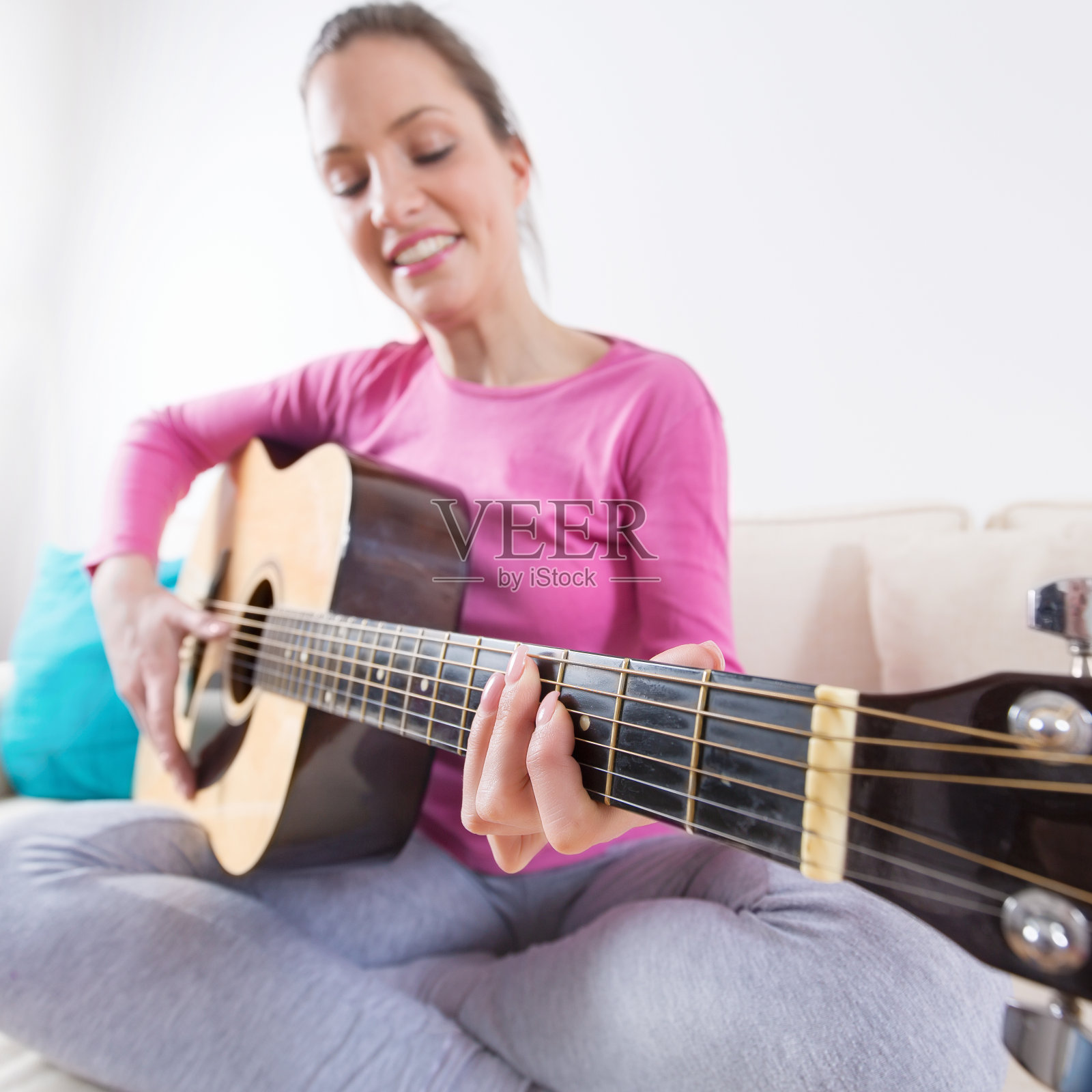 年轻女子坐在沙发上弹原声吉他照片摄影图片