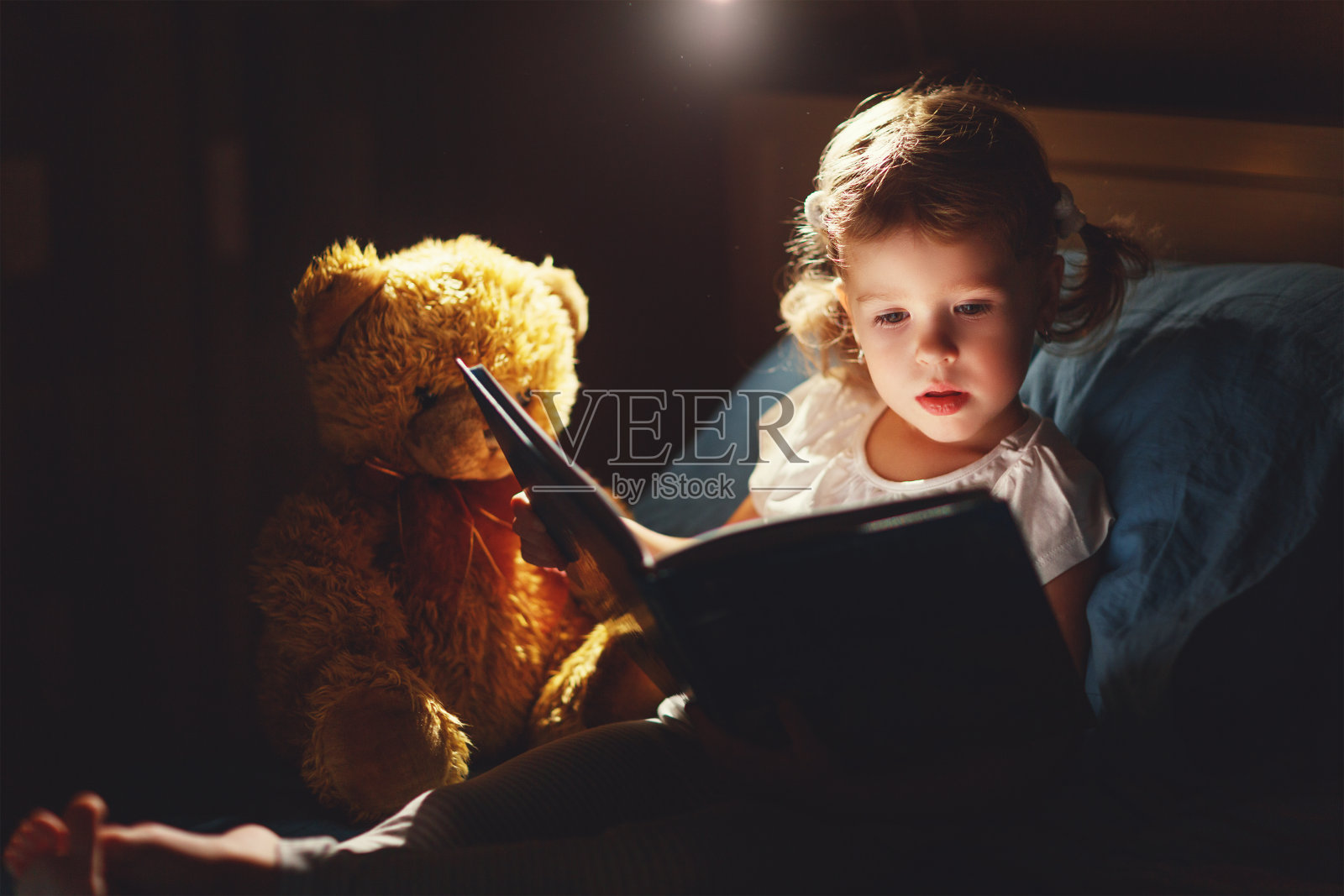 小女孩在床上看书照片摄影图片