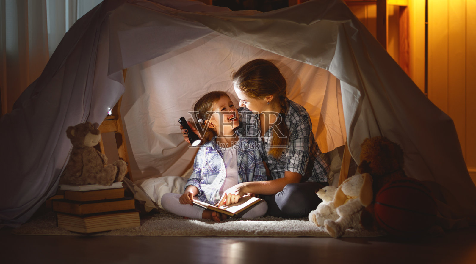 母亲和孩子在睡觉前拿着一本书和一个手电筒照片摄影图片