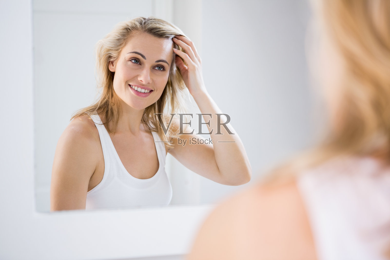 一名年轻女子在浴室镜子前检查头发照片摄影图片