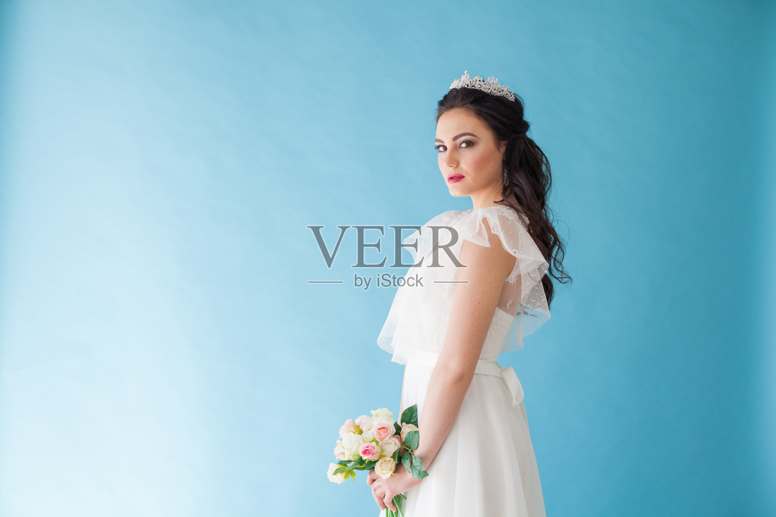 公主新娘在白色的裙子与一个皇冠上的蓝色背景照片摄影图片